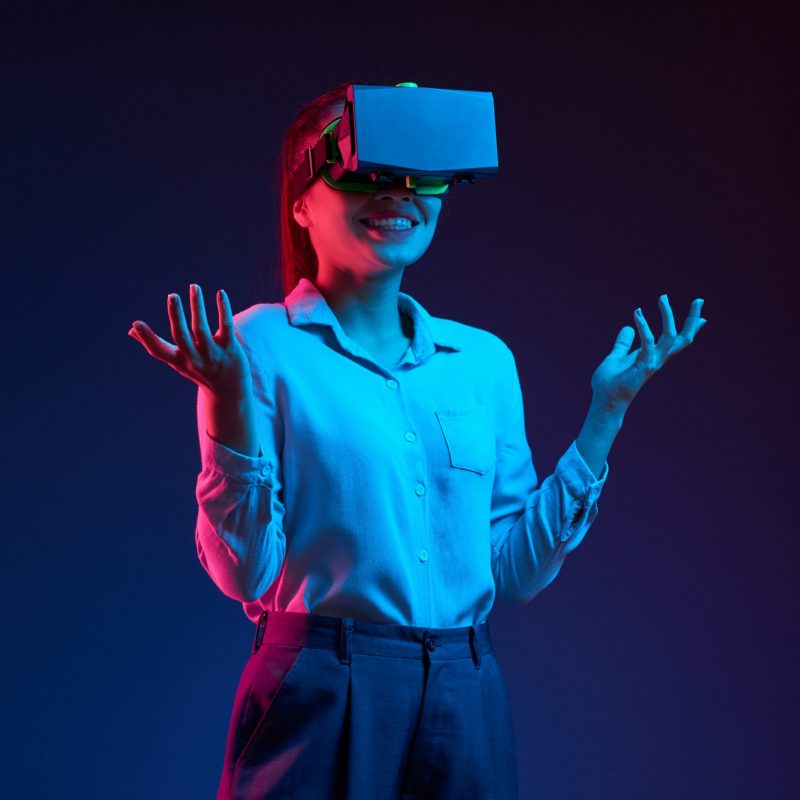 Cheerful smiling Asian business lady using vr glass to communicate with coworkers